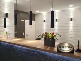 Una reception con un cartello che riporta "RECEPTION Rheingoldhotel", piante in vaso e lampade a sospensione.