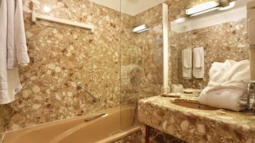 A bathroom with a marble floor, a bathtub, a sink, and a mirror.