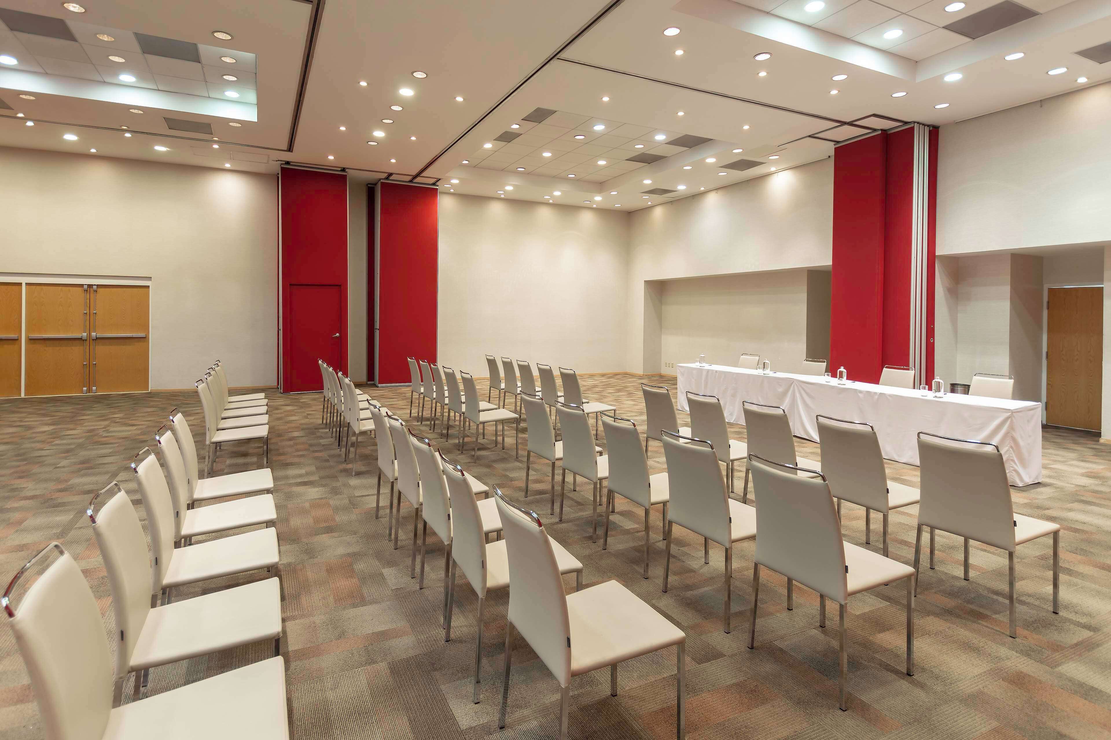 A conference room with rows of chairs, a long table, and a presentation screen.