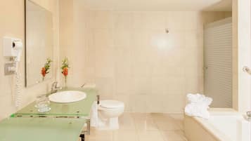 Un baño moderno con lavabo de vidrio, inodoro y bañera.