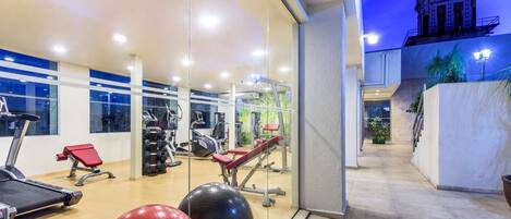 A gym with exercise equipment, a treadmill, and a red exercise ball.