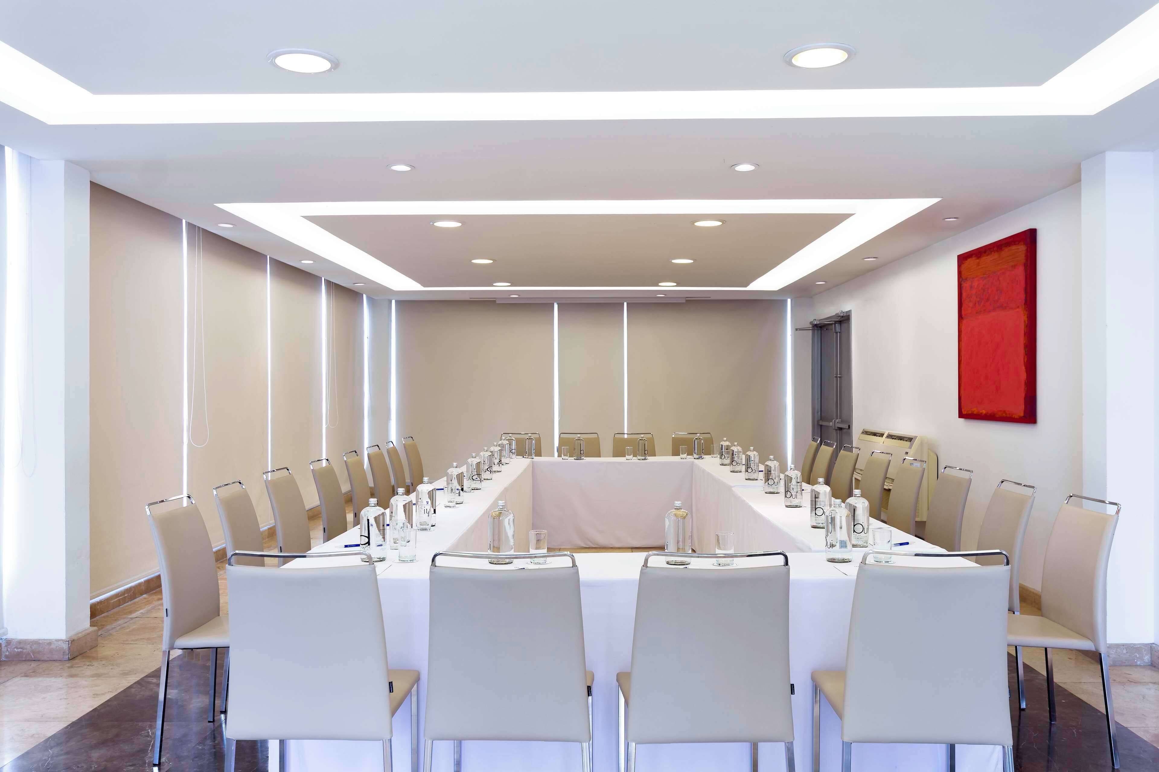 A conference room with a long table, chairs, and a red abstract painting on the wall.