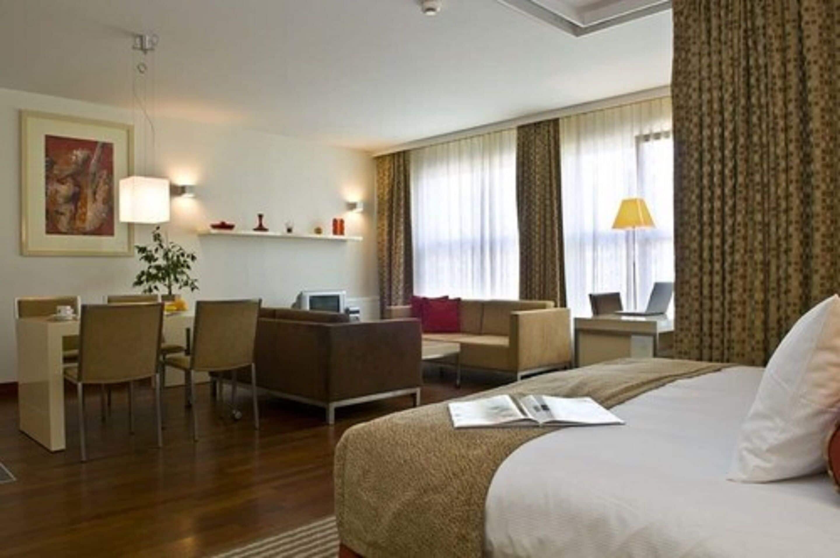 Une chambre d’hôtel avec un lit, un bureau, une chaise, un canapé et une lampe.