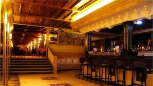 A bar area with a staircase leading to a seating area, featuring a bar counter and chairs. - Hotel Des Iles (Essaouira)