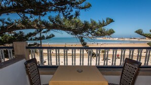 A balcony with a table and chairs overlooking a beach. - Hotel Des Iles (Essaouira)