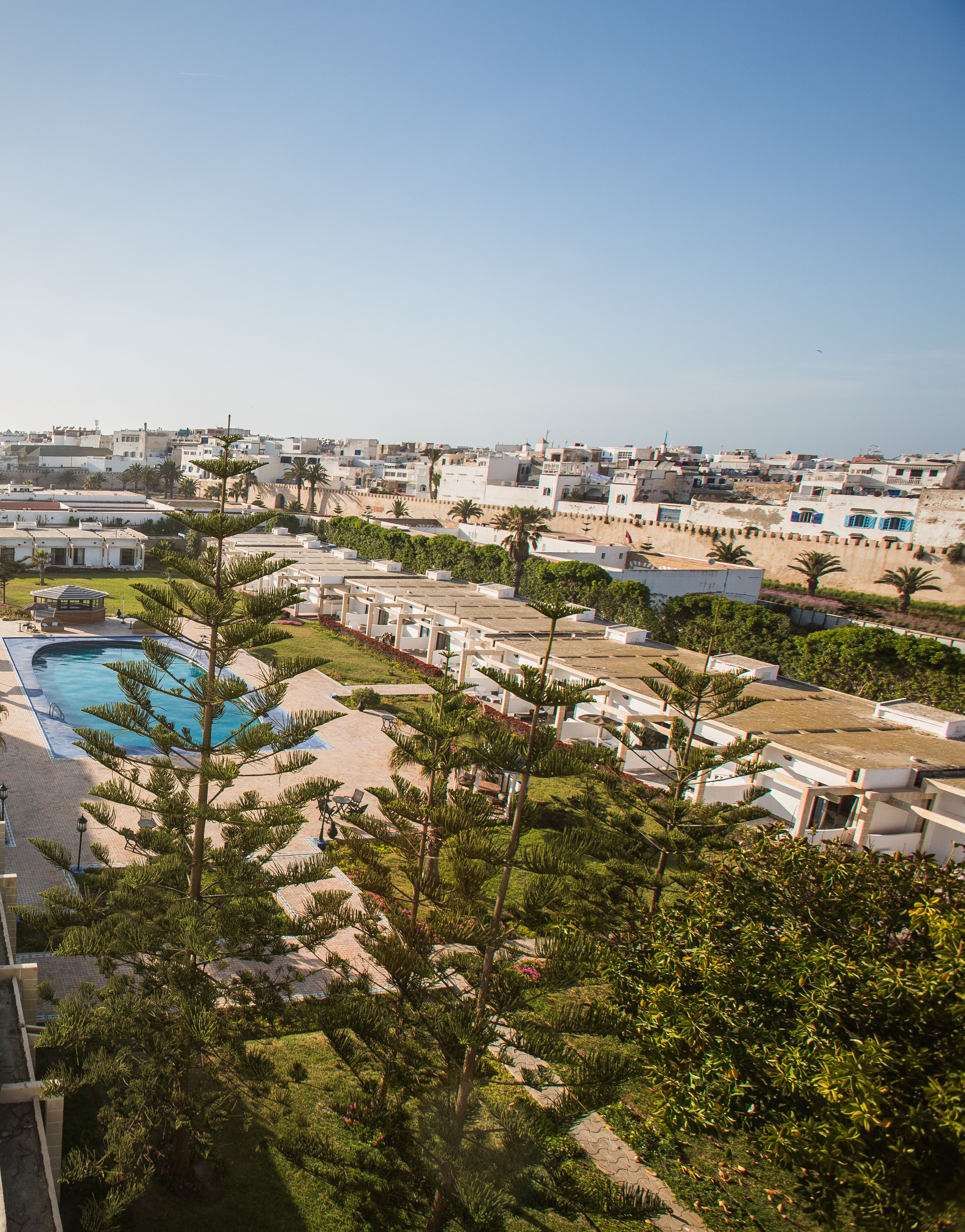 Un resort con piscina, palmeras y vistas a la ciudad.