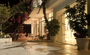 An outdoor seating area with tables and chairs, surrounded by potted plants and trees. - Hotel Iris (Rhodes)