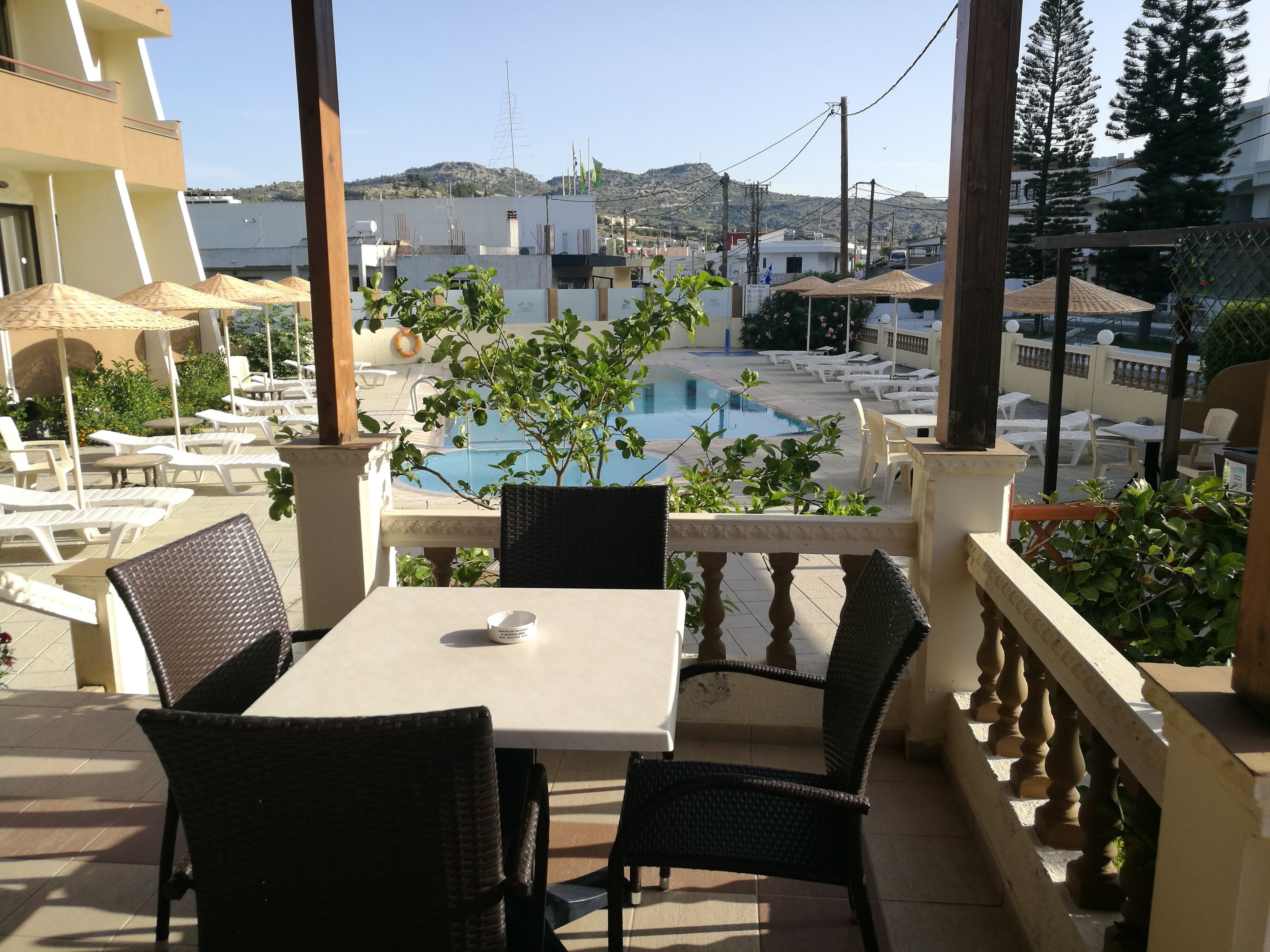 Une terrasse avec une piscine, des chaises longues et une table avec une tasse.