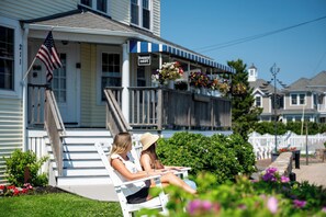 A residential building with a porch, a flag, and flower baskets. - The Beach House Inn (Kennebunk)