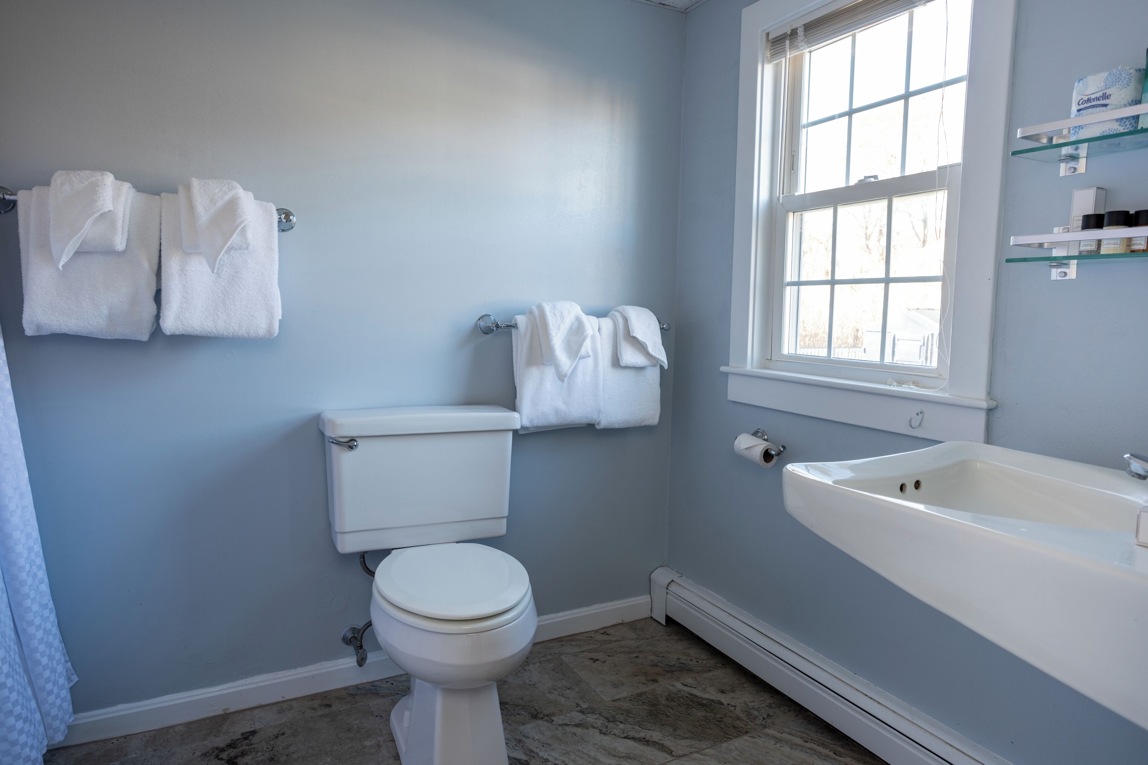 Une salle de bain avec des toilettes, un lavabo et une fenêtre.