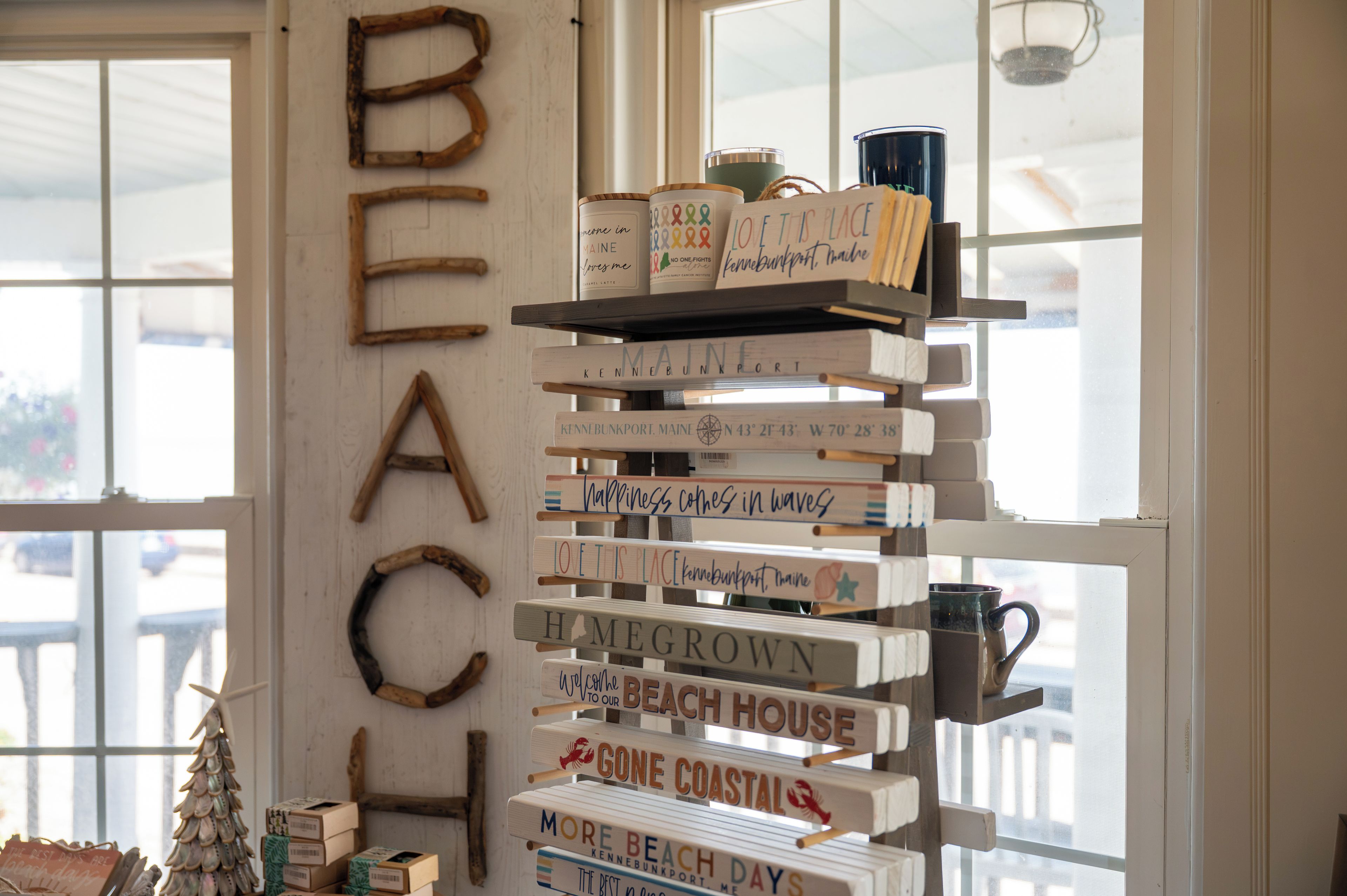 A wooden sign with the word 'BEACH' and a shelf with various items including a mug and a candle.