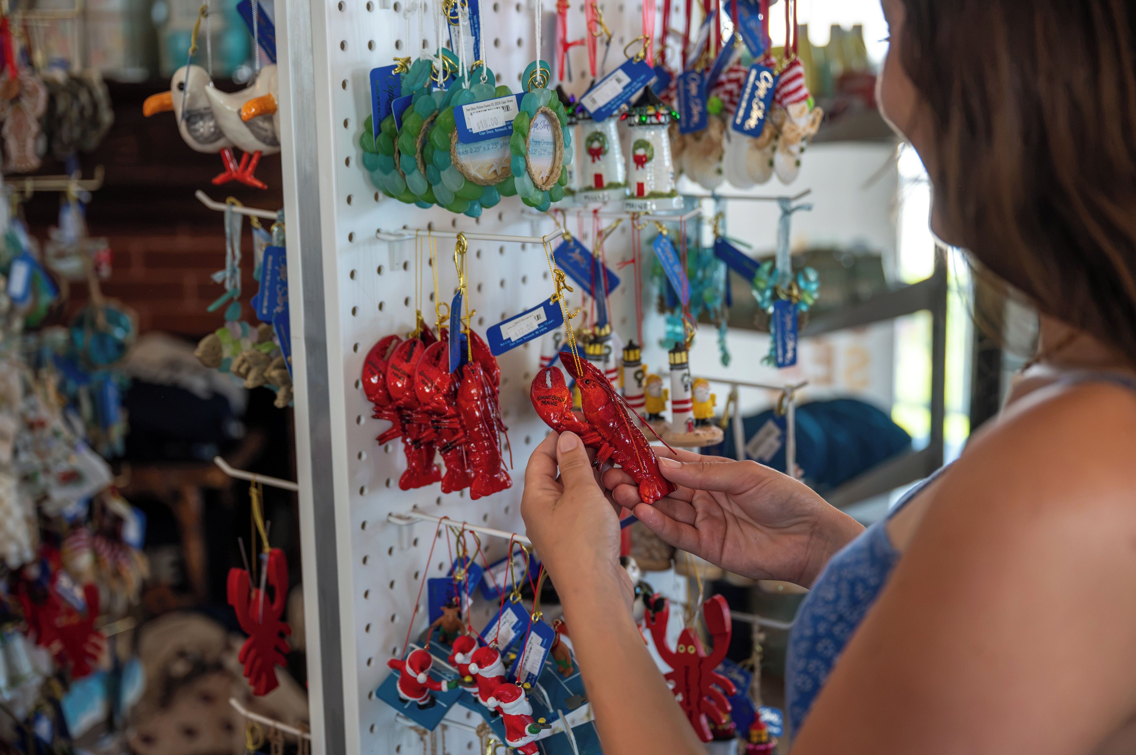 A person examining various holiday ornaments on a pegboard display.