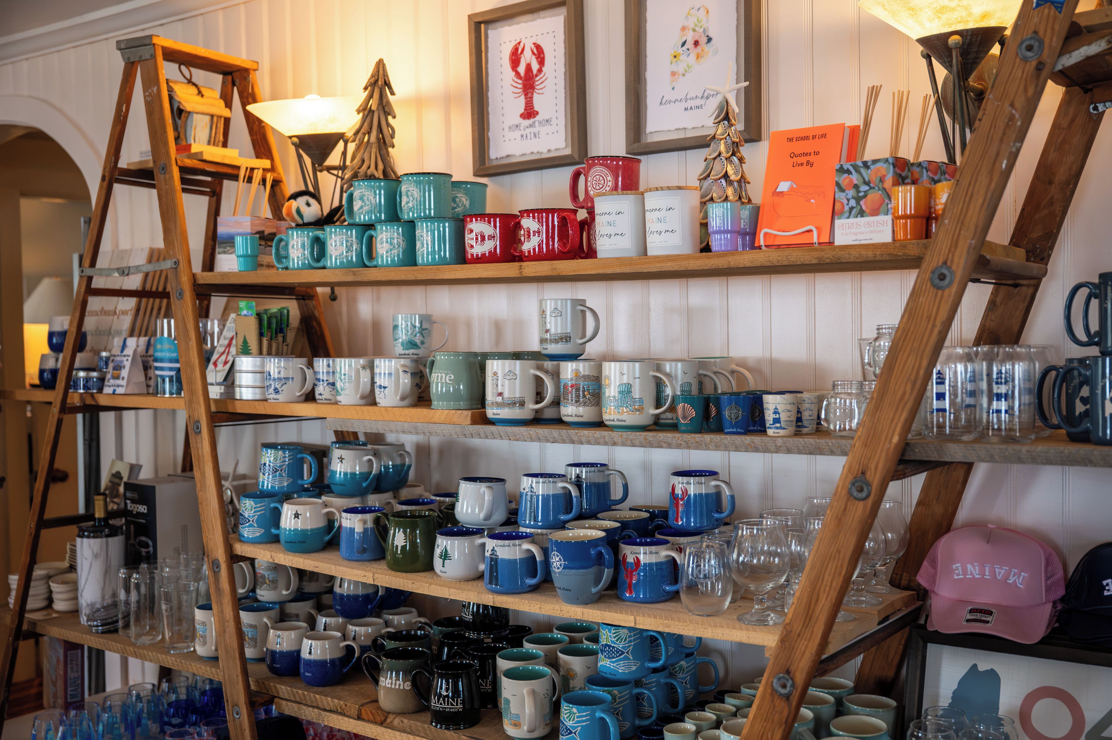 A display of various ceramic mugs and glassware on wooden shelves.
