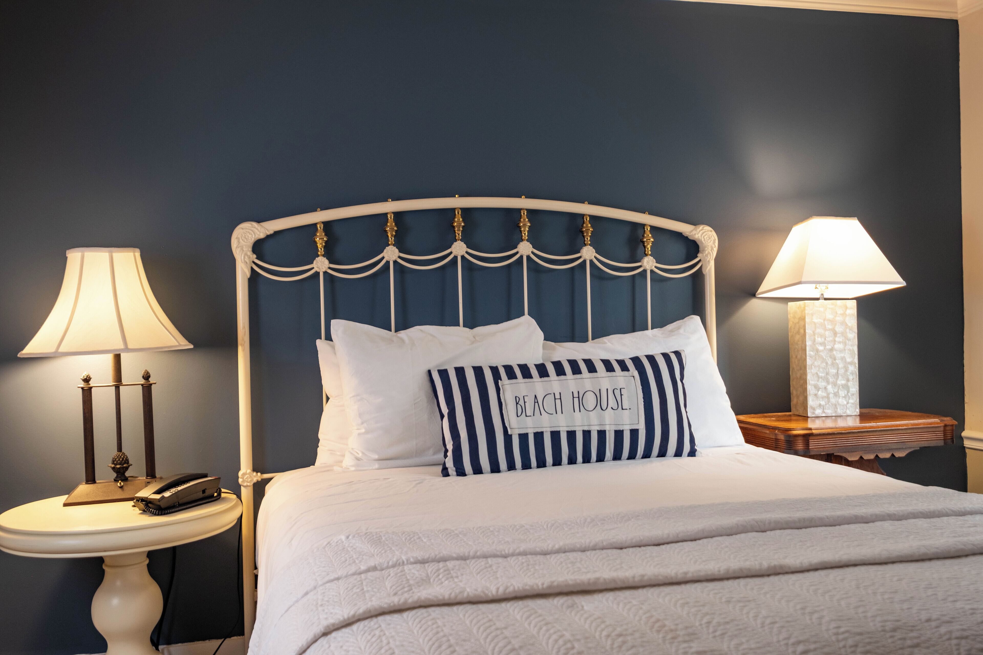 A neatly made bed with a headboard, two bedside tables, and lamps.