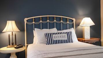 A neatly made bed with a headboard, two bedside tables, and lamps.