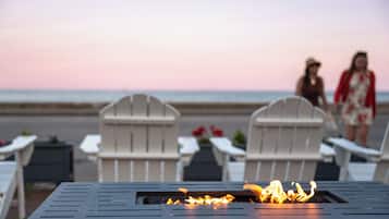 Un espacio de relax frente al mar, con sillas tipo Adirondack y una fogata.