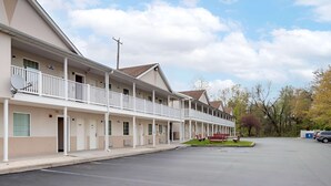 Un motel con paseo techado, varias habitaciones y estacionamiento.