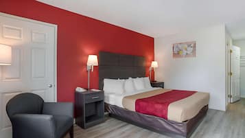 A hotel room with a bed, two bedside tables, a chair, a door, and a wall with a map artwork.