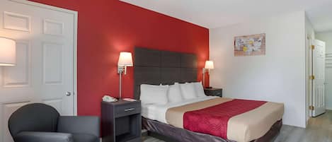 A hotel room with a bed, two bedside tables, a chair, a door, and a wall with a map artwork.