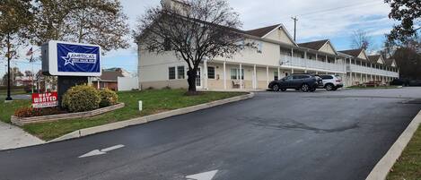 Un motel con un letrero, una zona de estacionamiento y un edificio con varias unidades.