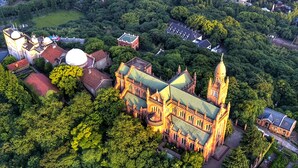 An aerial view of a historic building surrounded by dense greenery, featuring a prominent tower and multiple domes. - Le Méridien Shanghai Sheshan (Shanghai)