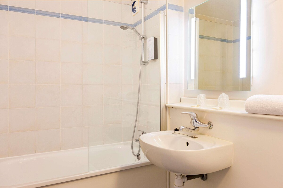 A bathroom with a bathtub, a sink, and a mirror.