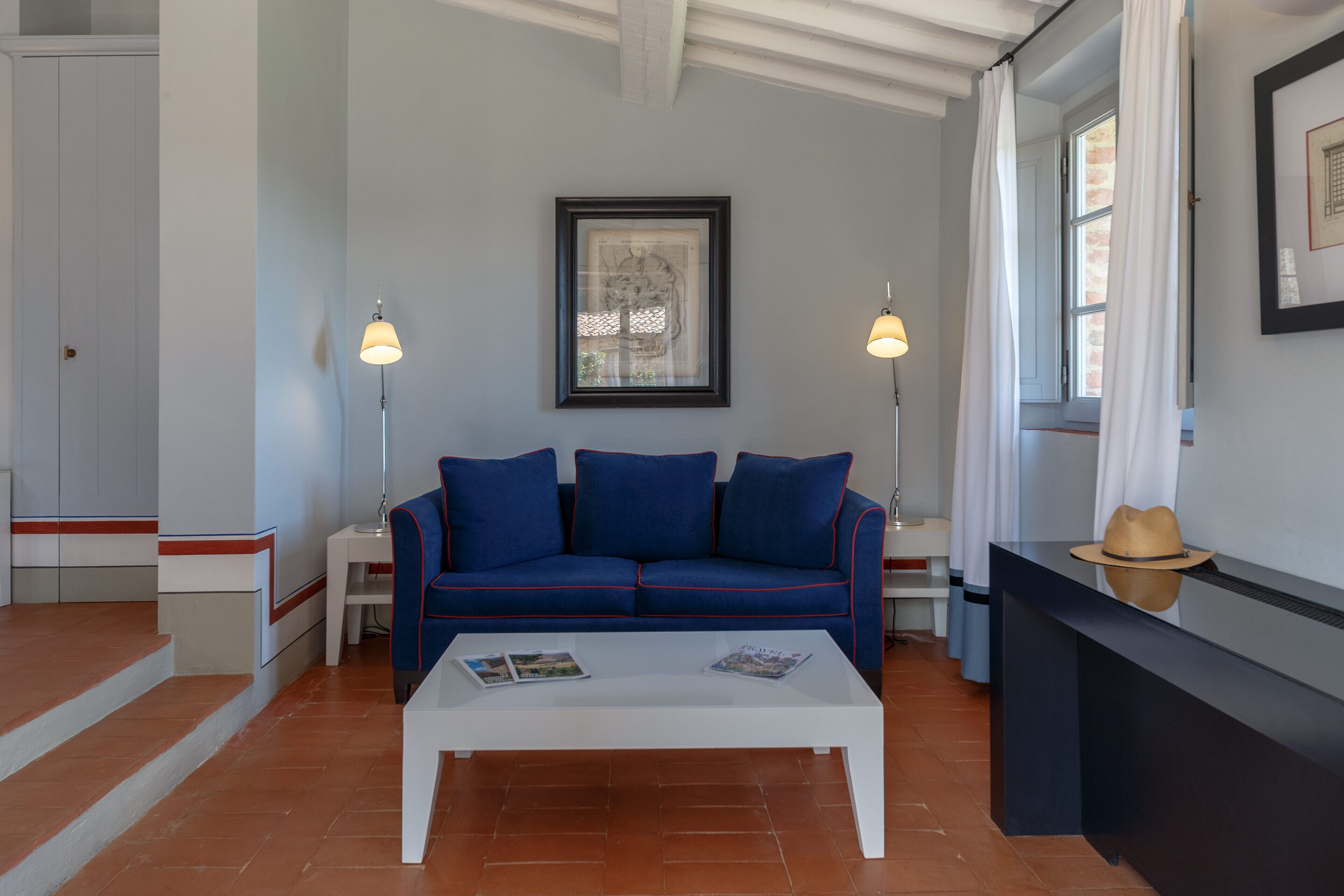 A living room with a blue sofa, white coffee table, and two floor lamps.
