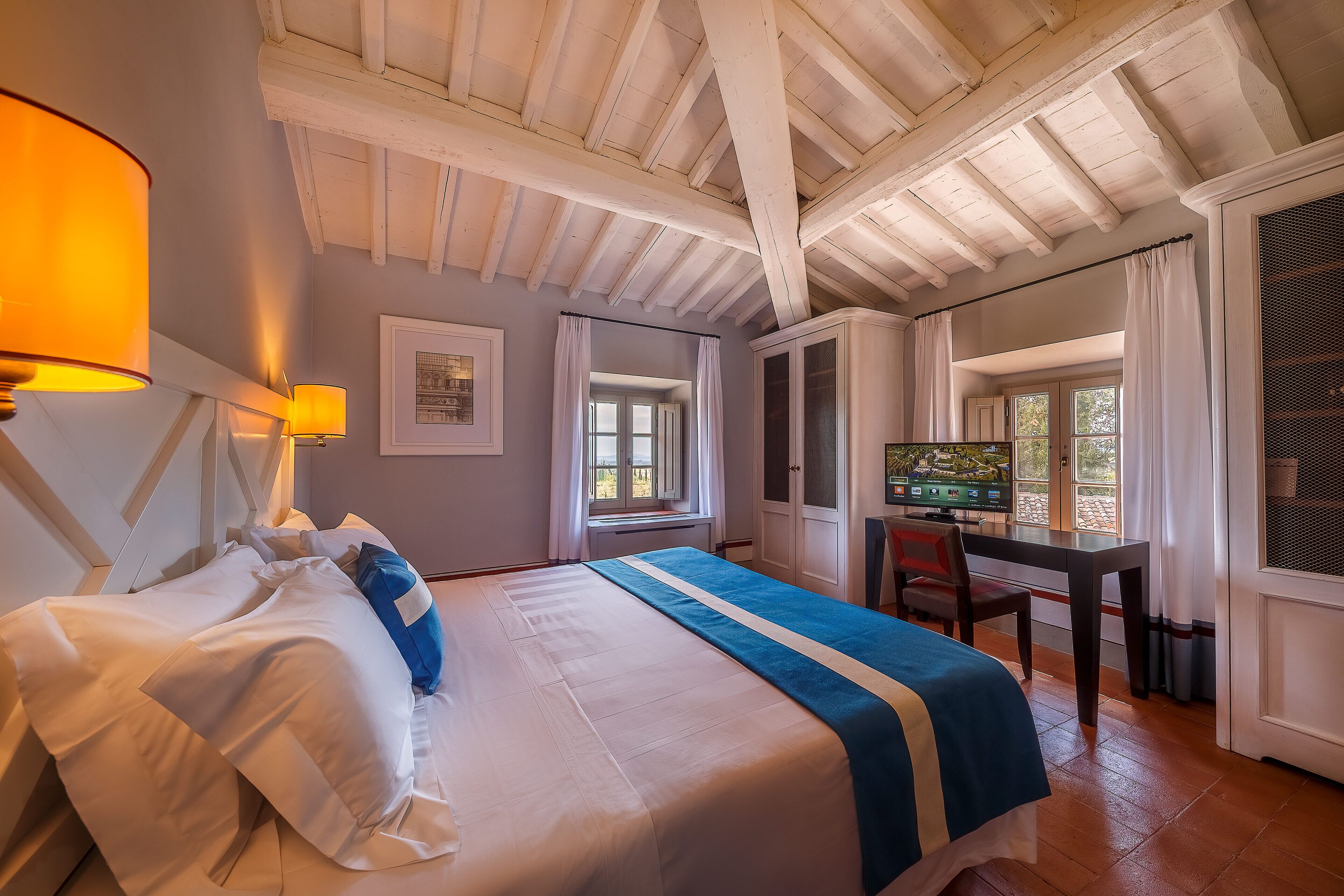 A bedroom with a bed, a desk, and a window.