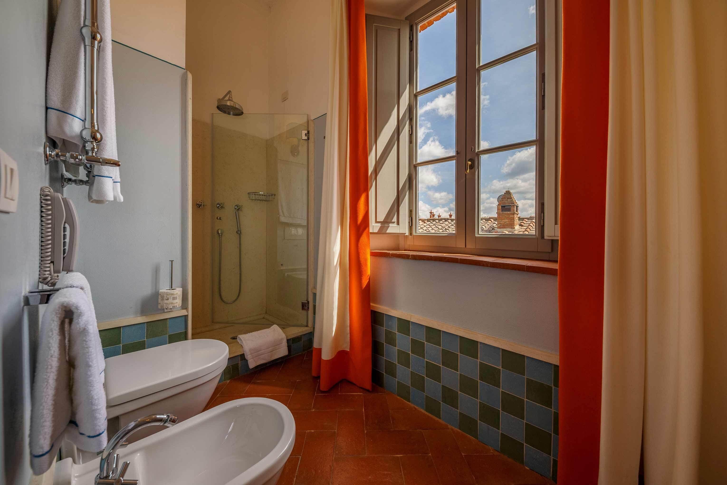 A bathroom with a bathtub, shower, and a window with curtains.