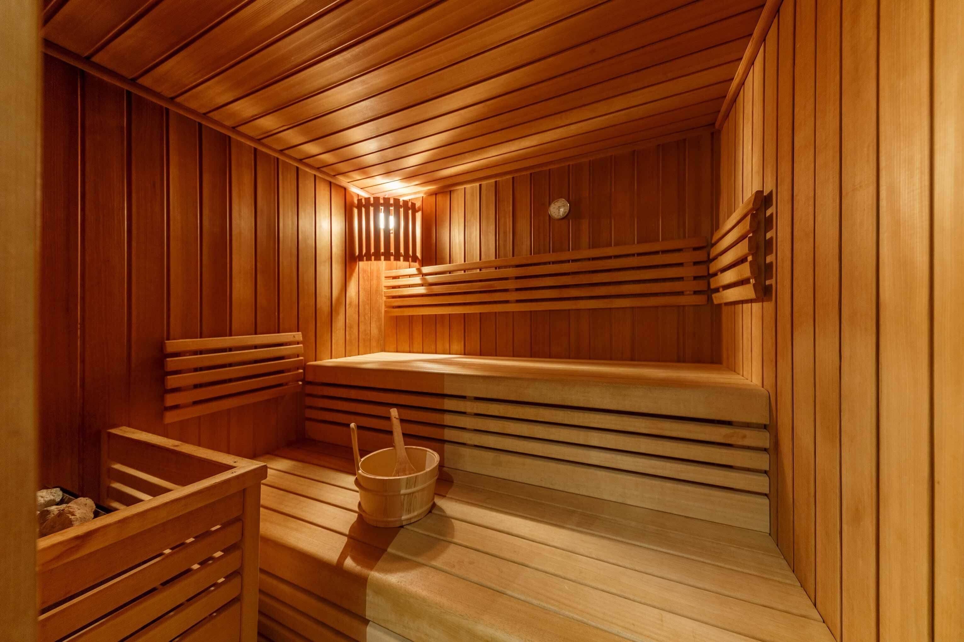 Eine Sauna mit Holzbänken und einem Eimer sowie einer Bürste.