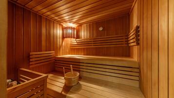 Eine Sauna mit Holzbänken und einem Eimer sowie einer Bürste.