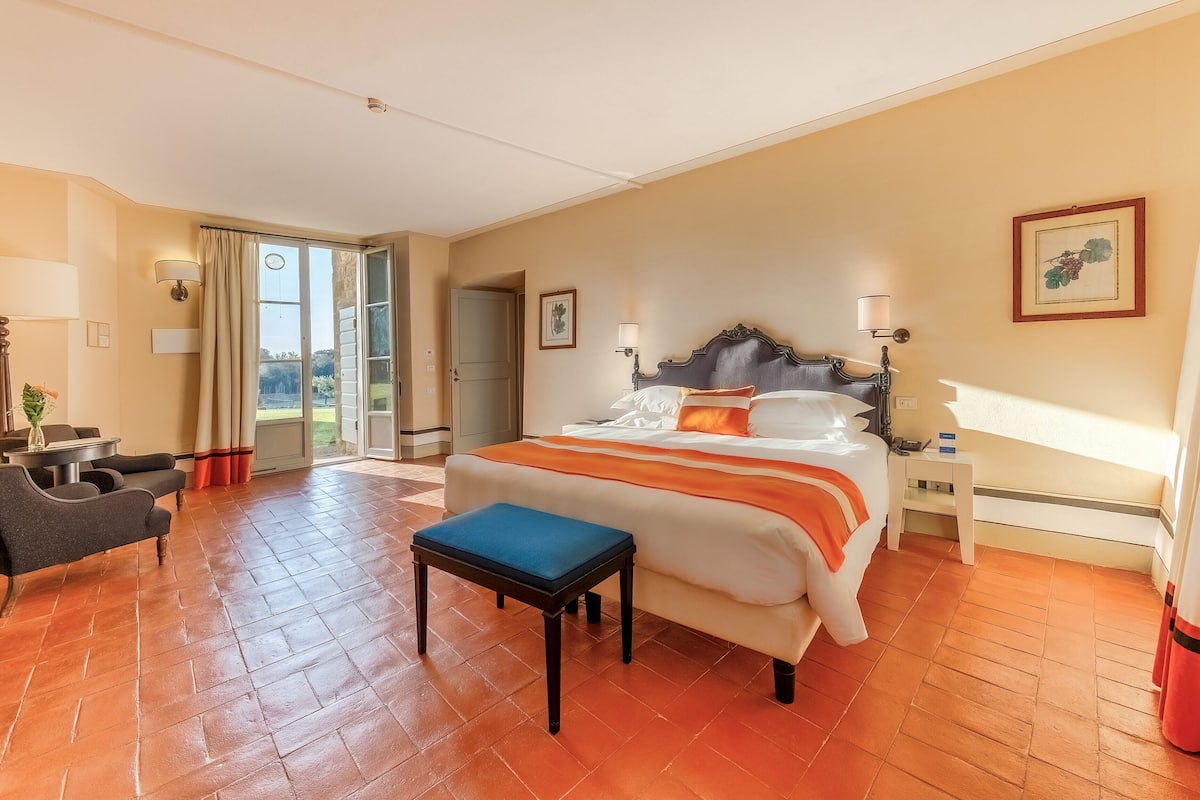Een hotelkamer met een groot bed, een bureau, een stoel en uitzicht op de omgeving.