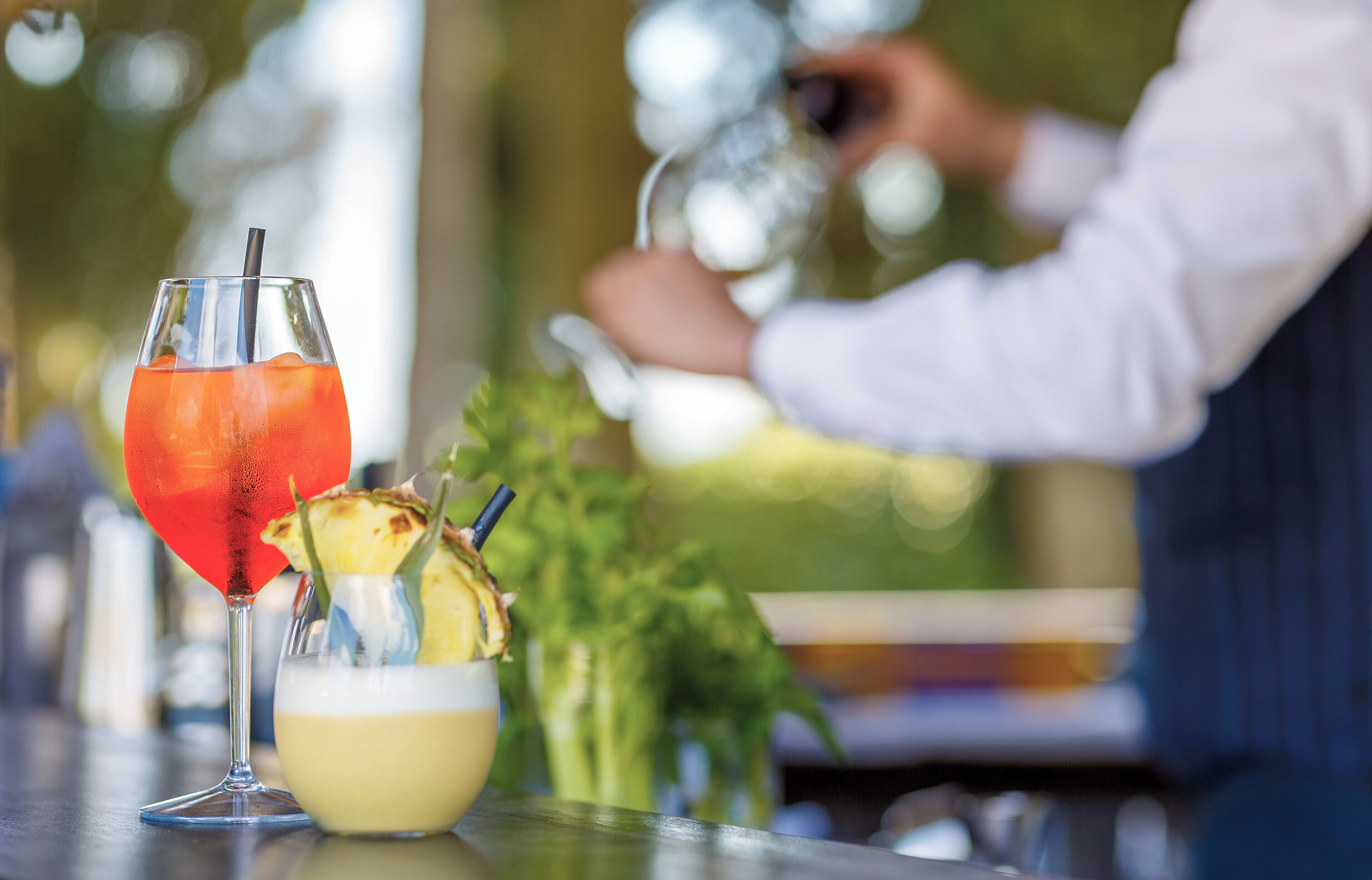 A bar setting with a drink in a glass and a cocktail shaker in the background.