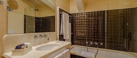 A bathroom with a double sink, a bathtub, a shower, and a large mirror.