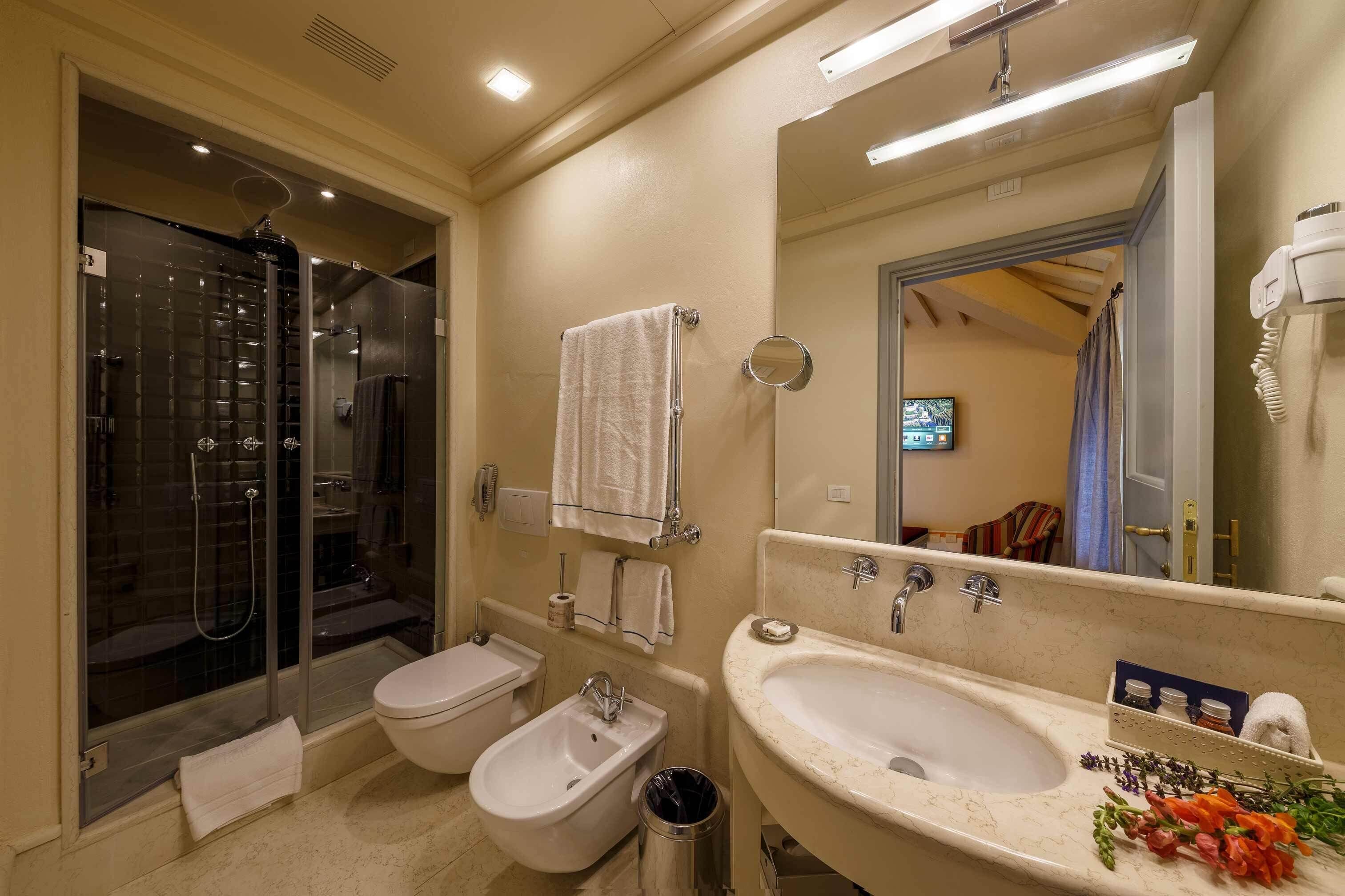 Ein modernes Badezimmer mit Duschkabine, Bidet, Waschbecken mit Spiegel und Toilette.