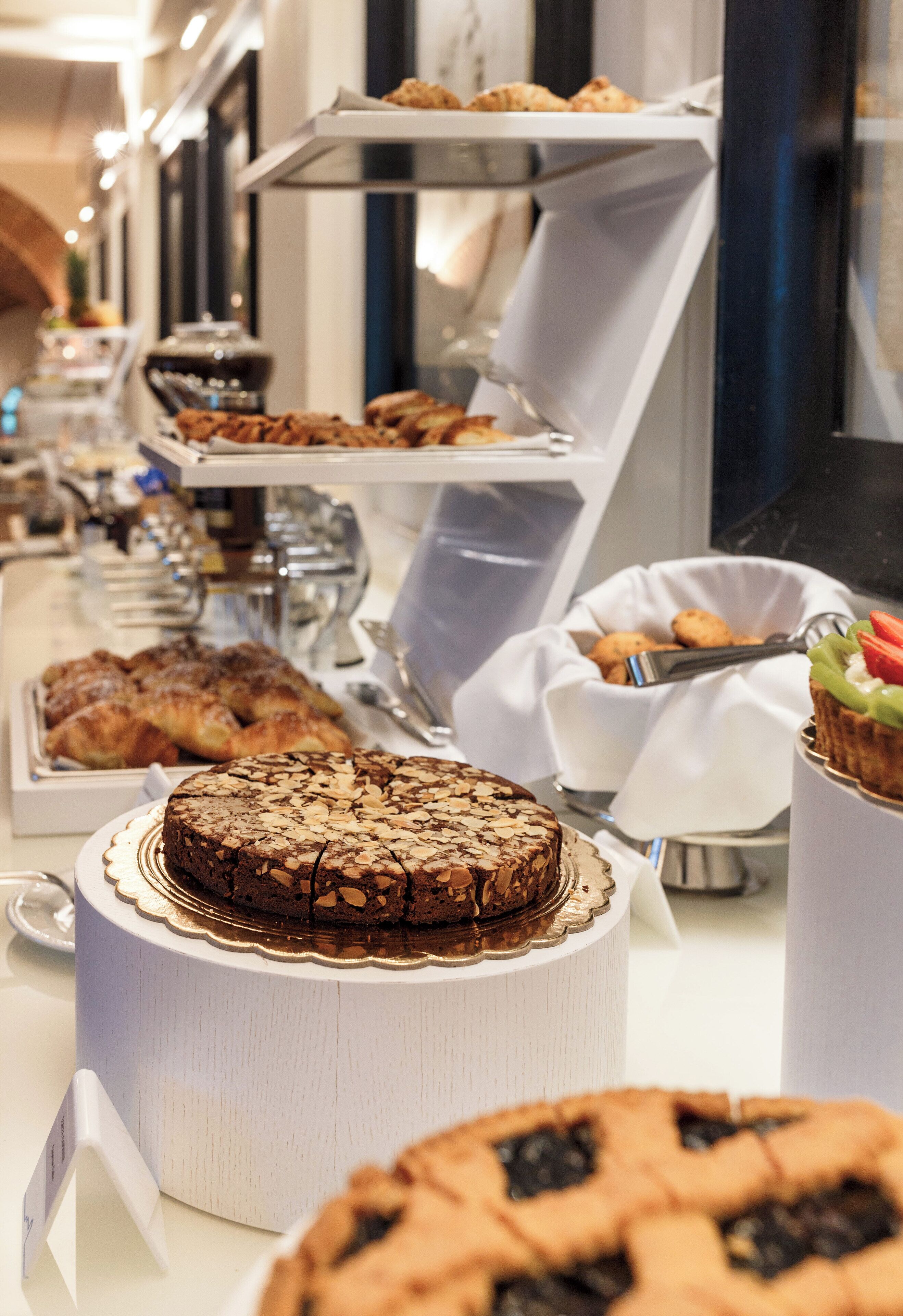 A buffet with various baked goods including a large cake, pastries, and pies.
