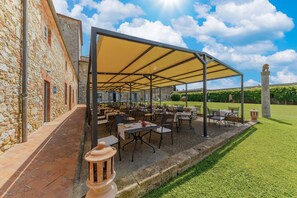 An outdoor patio area with stone walls, tables, and chairs under a canopy. - Borgo Scopeto Wine & Country Relais (Castelnuovo Berardenga)