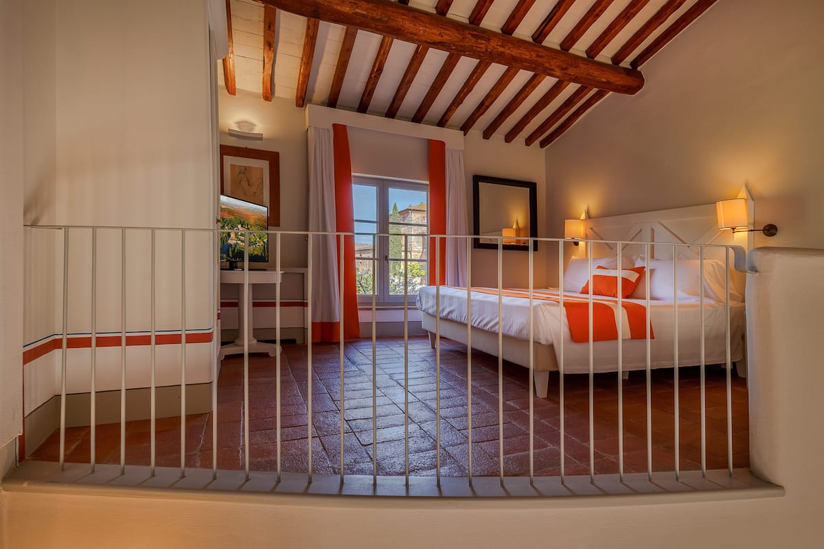 Een slaapkamer met een bed, een bureau en een raam met gordijnen.