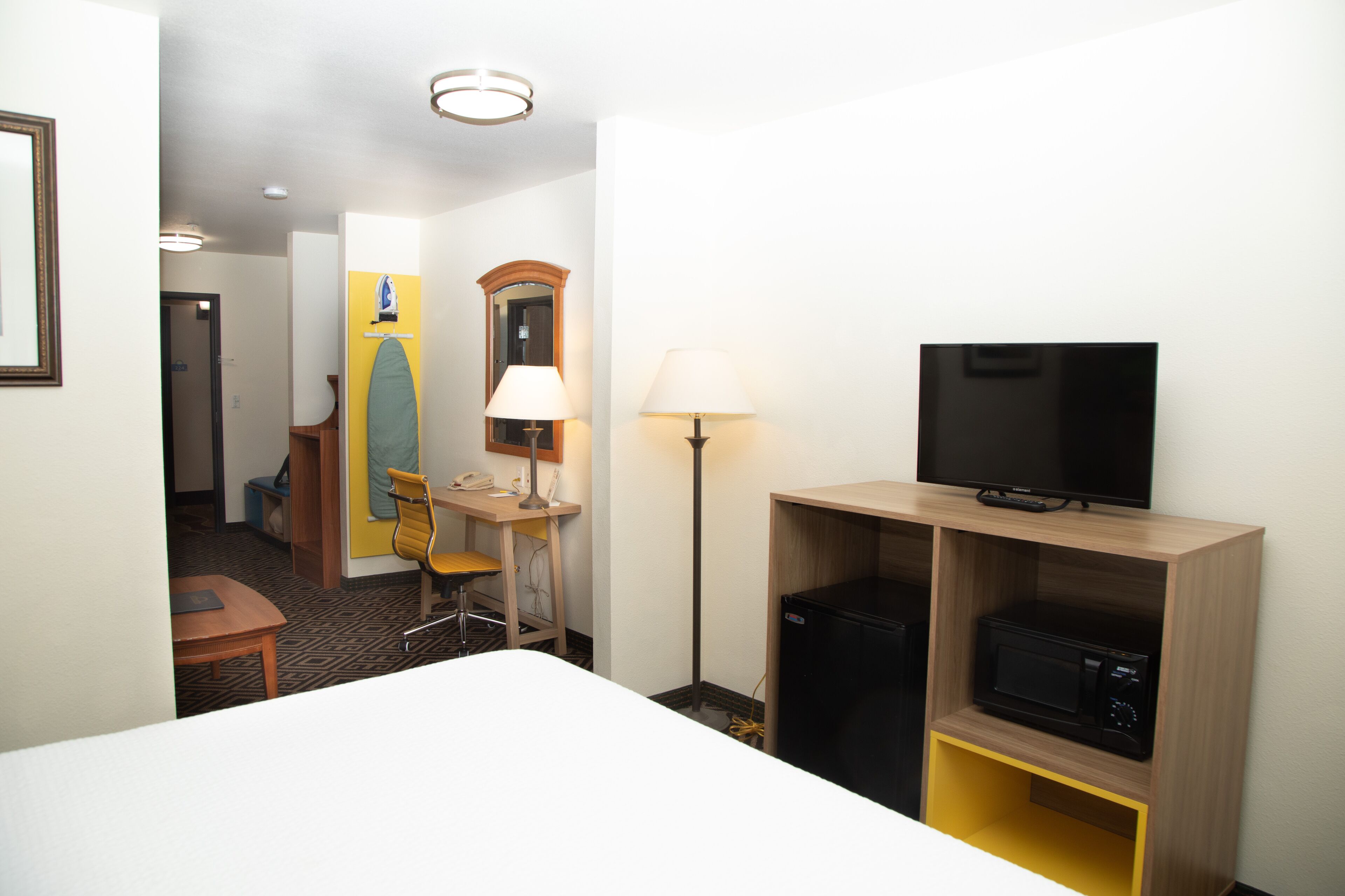 Une chambre d’hôtel équipée d’un lit, d’un bureau avec une chaise, d’une télévision, d’une lampe et d’un four à micro-ondes.