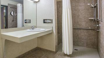 Une salle de bain moderne équipée d’un lavabo, d’un miroir, d’une douche et de barres d’appui.