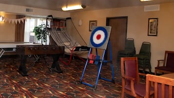 Een kamer met een pooltafel, een dartbord en een tafelvoetbaltafel.