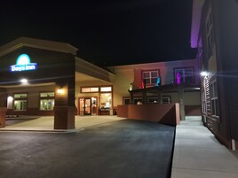 Un Days Inn con una entrada bien iluminada, un área exterior cubierta y un edificio con balcón.