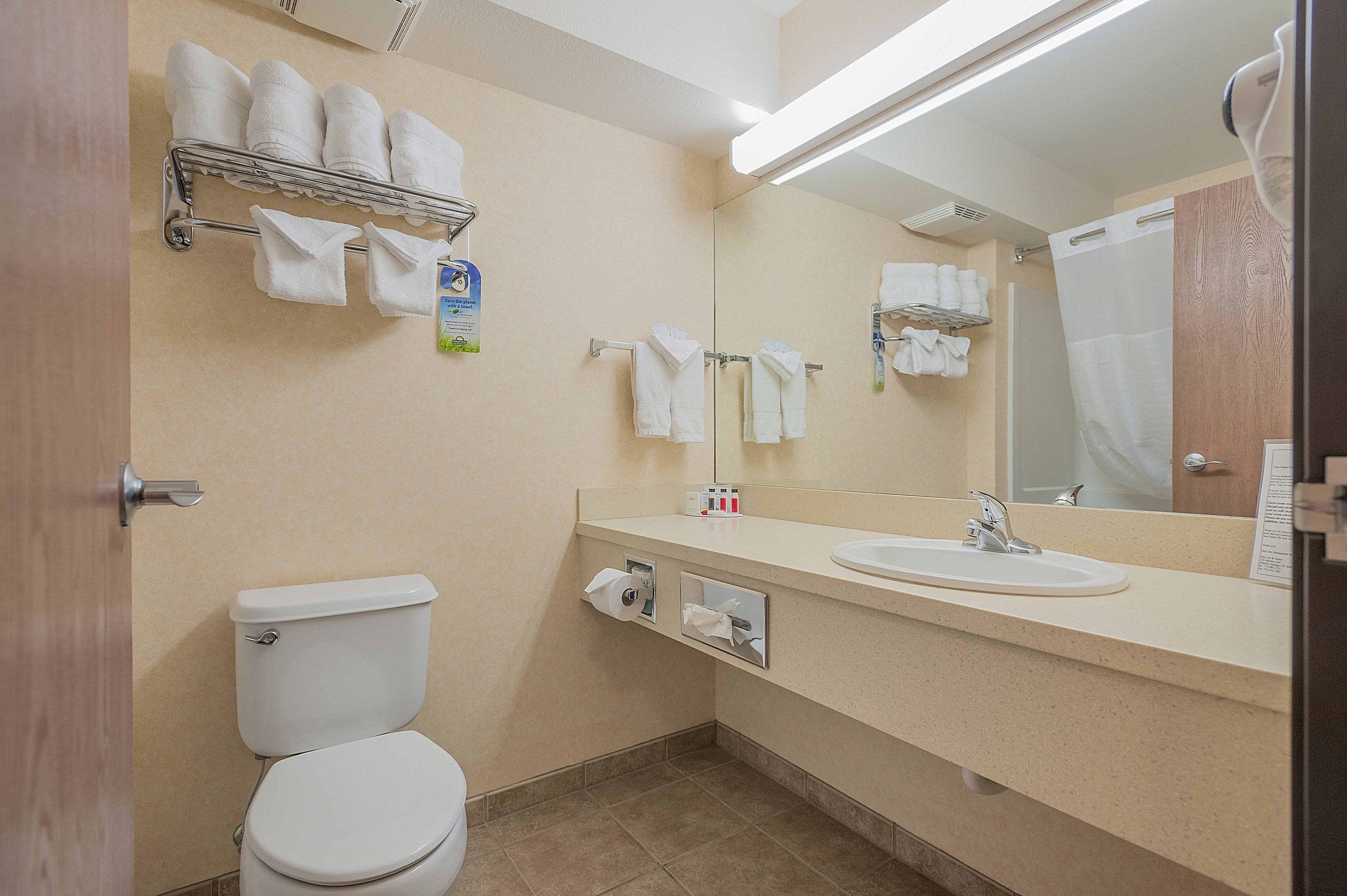 A bathroom with a toilet, sink, mirror, towel rack, and shower curtain.