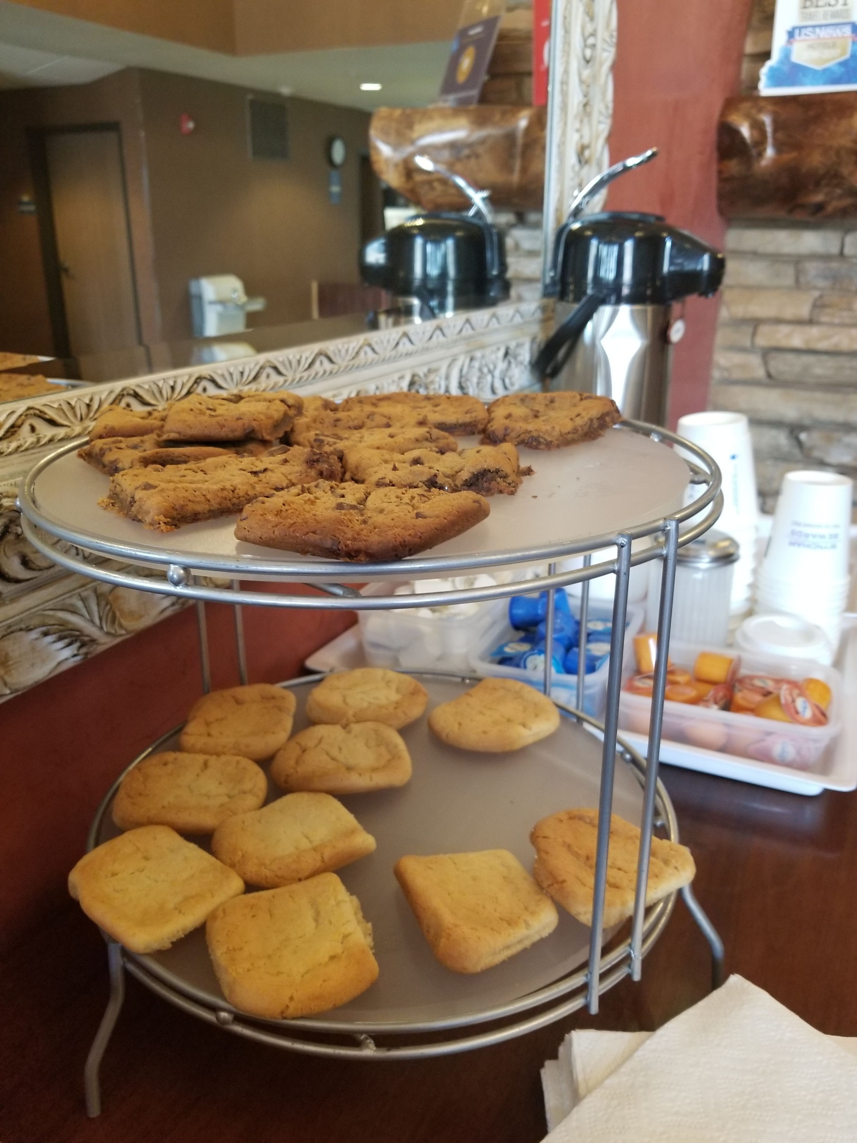 Un bufé con bandejas de galletas y una máquina de café al fondo.