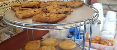 A buffet with trays of cookies and a coffee machine in the background.