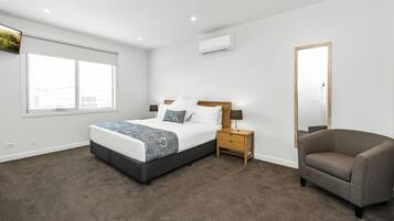 A bedroom with a bed, nightstand, chair, and window.