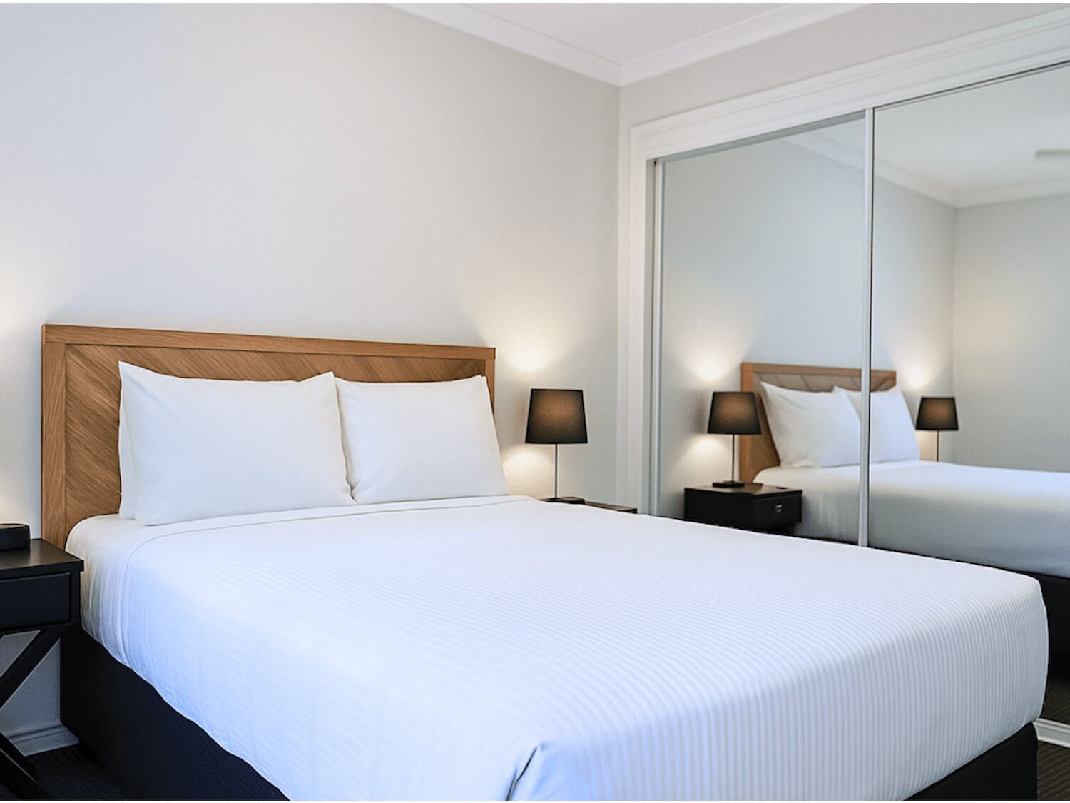 Ein Hotelzimmer mit einem großen Bett, zwei Nachttischen und einem Spiegel.
