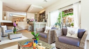 A modern living room with wicker furniture, a glass coffee table, and a view of the outdoor area.