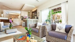 Una sala de estar moderna con muebles de mimbre, una mesa de centro de vidrio y vistas al área exterior.