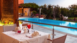 Mesa de comedor para dos con vista a una piscina.